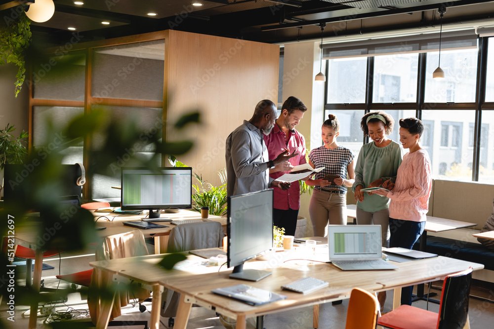 Multiracial male and female colleagues discussing business plan during meeting in creative office